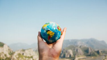 Hand holding a globe against a mountain background symbolizing travel and exploration.